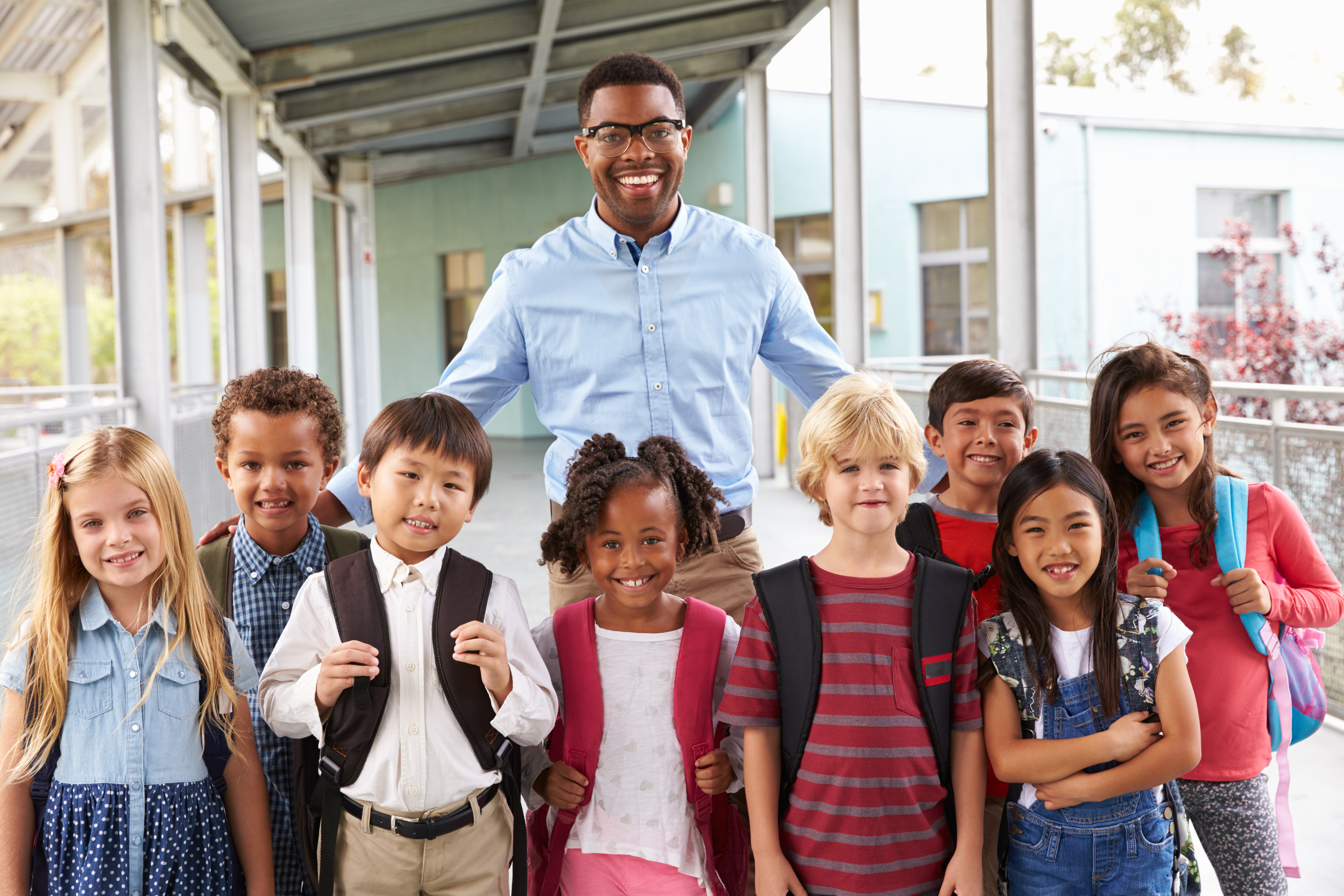 Young male teacher standing with a classroom of students.