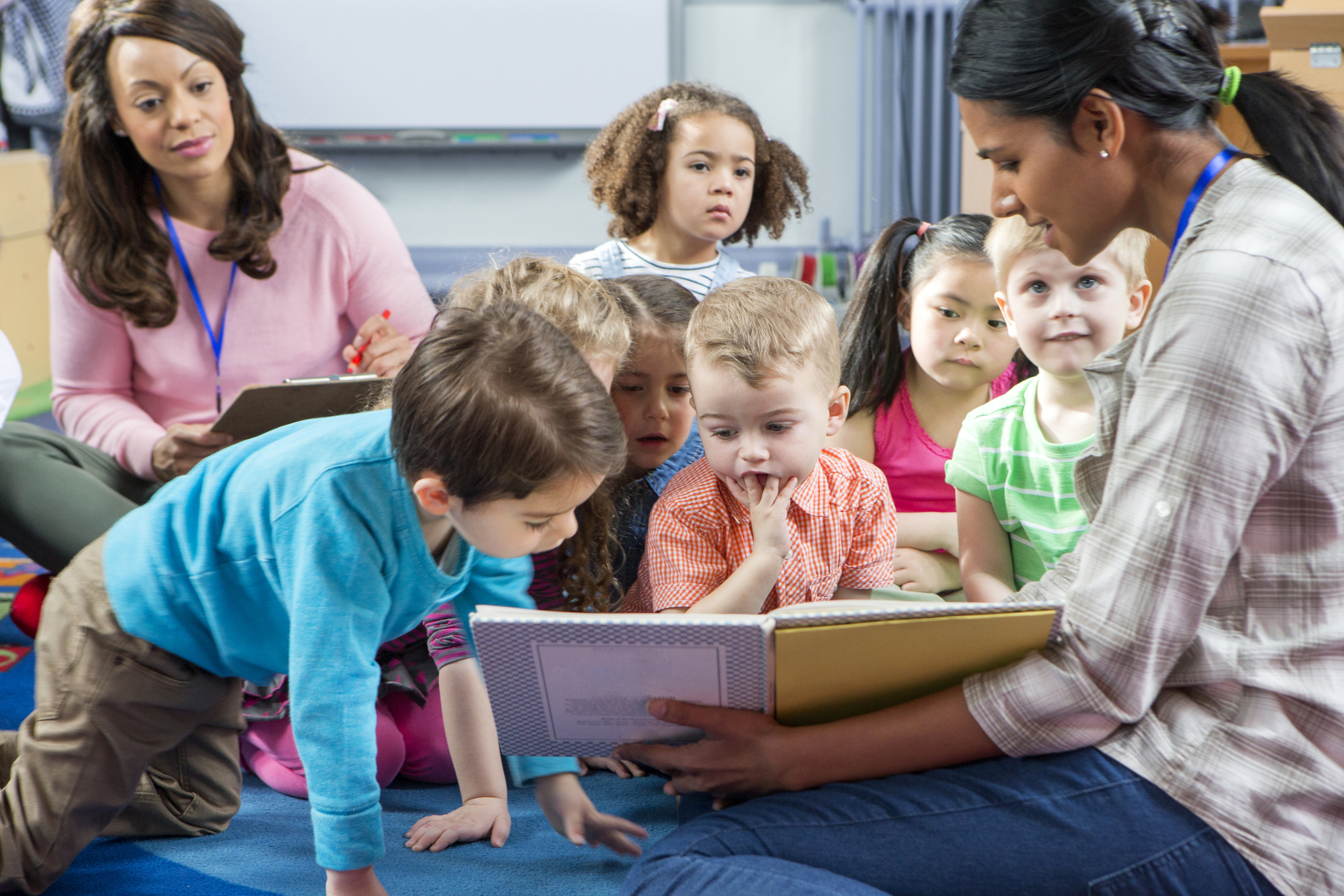 Teacher and Teacher's assistant reading to classroom of preschool children.